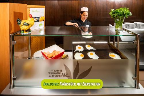 a woman standing in a kitchen preparing food at AHORN Waldhotel Altenberg in Kurort Altenberg