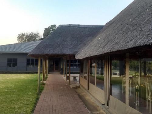 a building with a thatched roof and a walkway at Vista ORT in Kempton Park