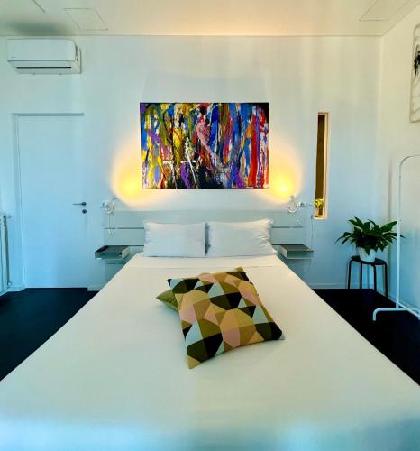 a bedroom with a white bed with a painting on the wall at Residenza d'Artista al Conservatorio in Salerno
