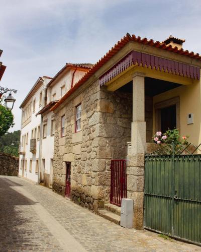 a stone house with a green gate on a street at Casa das Fontes in Ponte da Barca