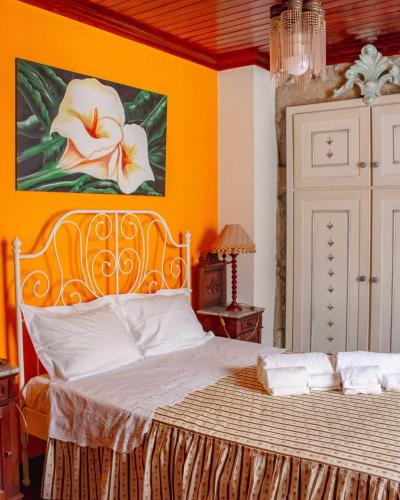 a bedroom with a bed with a painting on the wall at Casa das Fontes in Ponte da Barca