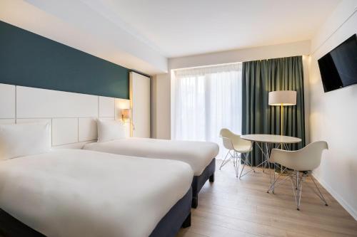 ブリュッセルにあるHotel Louiseのベッド2台とテーブルが備わるホテルルームです。