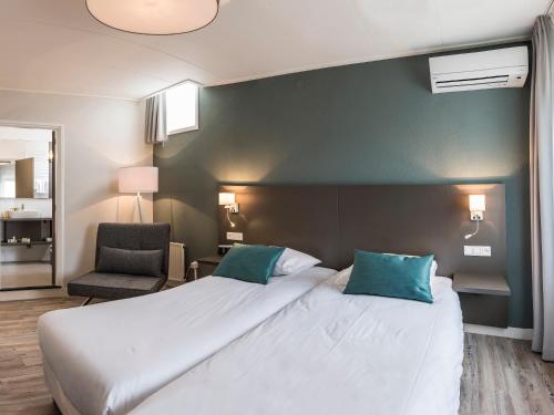 a bedroom with a large white bed and a chair at Het Wapen van Elst in Elst