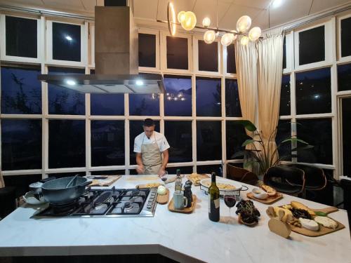 a man standing in a kitchen with a table with food at La Cantane Villa in Kundasang