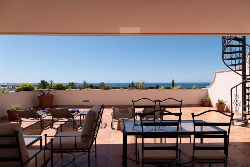 a patio with tables and chairs on a roof at Guadalpin Suites in Marbella