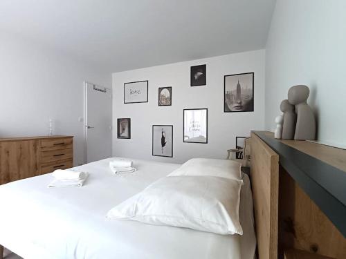 - une chambre dotée d'un lit blanc avec des photos sur le mur dans l'établissement Appartement spacieux avec terrasse en plein centre, à Anglet