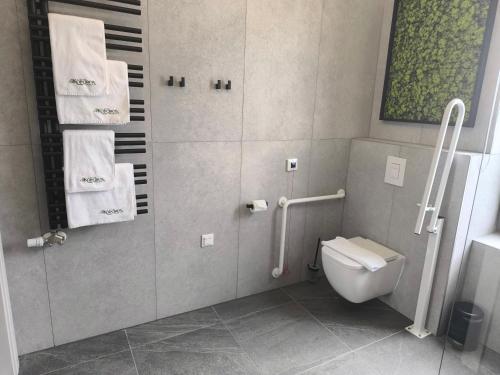 a bathroom with a toilet and a shower with towels at Hotel Kőporos Hercegkút in Hercegkút
