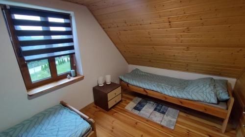 a bedroom with a bed and a window in a log cabin at Domek w Sadzie in Marcinowa Wola