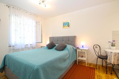 - une chambre avec un lit doté d'une couverture bleue et d'une table dans l'établissement Apartment Marija 1387, à Fažana