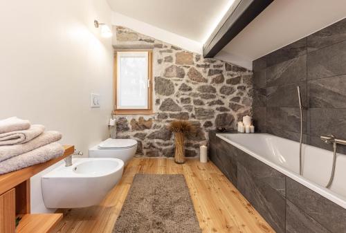 a bathroom with a stone wall and a tub and a sink at Villa Speronella in San Martino di Castrozza