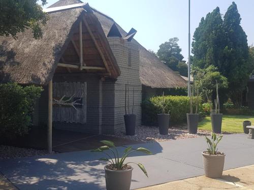 a small building with a thatched roof and two potted plants at Vista ORT in Kempton Park