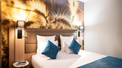 een slaapkamer met een bed met blauwe kussens bij Residhome Val d'Europe in Montévrain