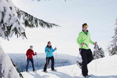 three people on skis on a snow covered slope at AHORN Hotel Am Fichtelberg in Kurort Oberwiesenthal