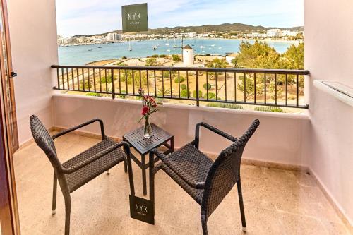 a table and chairs on a balcony with a view of the water at NYX Hotel Ibiza by Leonardo Hotels-Adults Only in San Antonio Bay