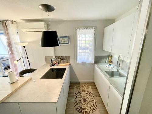 La cuisine est équipée de placards blancs, d'un évier et d'un comptoir. dans l'établissement PGH N18 - À 300m de la Plage avec Parking Privé, à La Grande Motte
