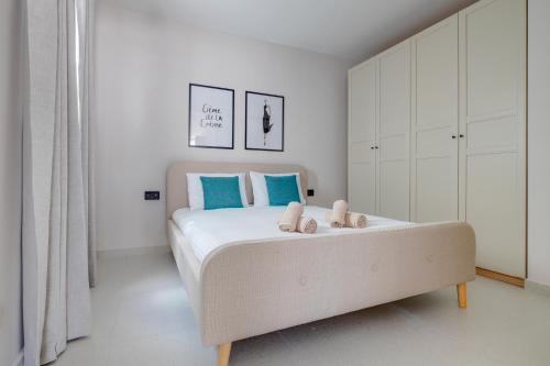 a white bedroom with a large bed with blue accents at Manoel De Vilhena Holiday Apartments in Il-Gżira
