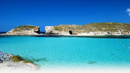 a view of a beach with blue water and rocks at Manoel De Vilhena Holiday Apartments in Il-Gżira