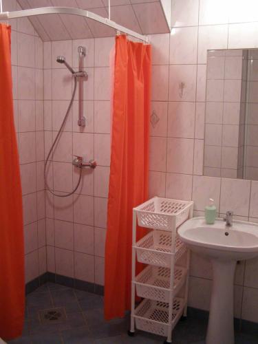 a bathroom with an orange shower curtain next to a sink at Tiia Guesthouse in Pärnu