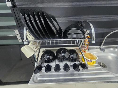 a dish rack with pans and utensils in a dishwasher at Homestay A&A in Sungai Petani
