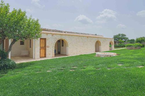 a building with a grassy yard in front of it at Masseria Casina Vitale in Ceglie Messapica