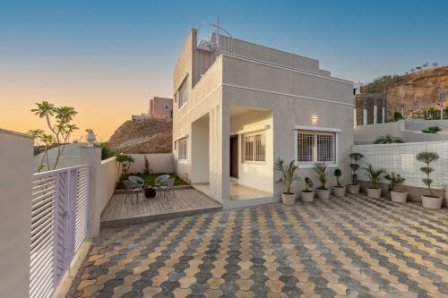 a white house with a courtyard with potted plants at ELIVAAS Shourya Zenna Luxe 3BHK Villa with Pvt Pool, Udaipur in Udaipur