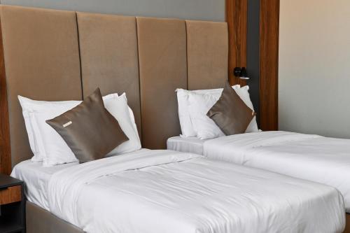 two beds in a hotel room with white sheets and pillows at Diamond Hotel Shymkent in Shymkent