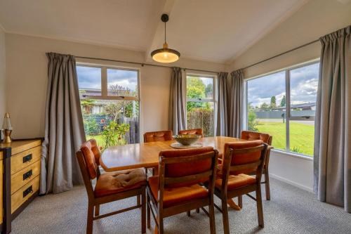 a dining room with a table and chairs and windows at 27 on Henry - Te Anau Holiday Home in Te Anau