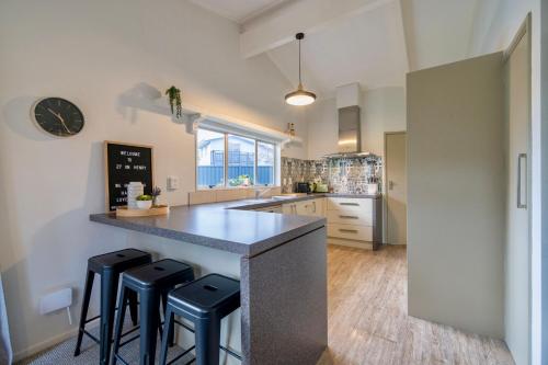 a kitchen with a counter and stools in a room at 27 on Henry - Te Anau Holiday Home in Te Anau