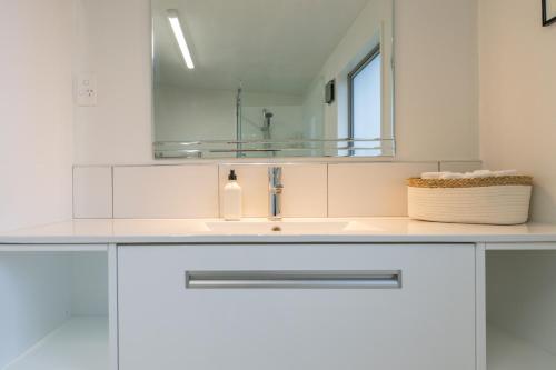 a white bathroom with a sink and a mirror at 27 on Henry - Te Anau Holiday Home in Te Anau