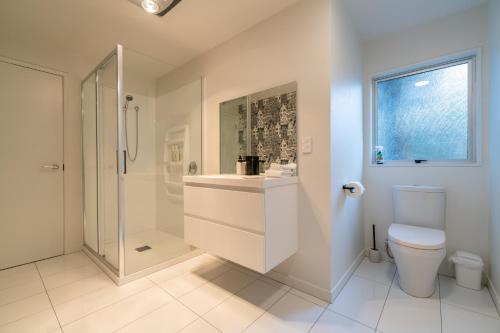 a white bathroom with a shower and a toilet at 27 on Henry - Te Anau Holiday Home in Te Anau