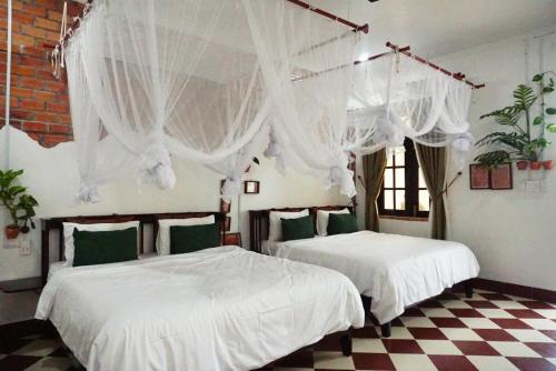 1 Schlafzimmer mit 2 Betten mit weißer Bettwäsche und Vorhängen in der Unterkunft Mekong Pottery Homestay, Green-Friendly & Boat Tour in Vĩnh Long