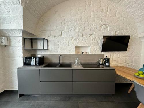 Una cocina con fregadero y una pared de ladrillo blanco. en Star White, en Ostuni