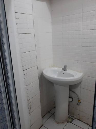 a bathroom with a white sink and a white wall at Mountains View Villa in Freetown
