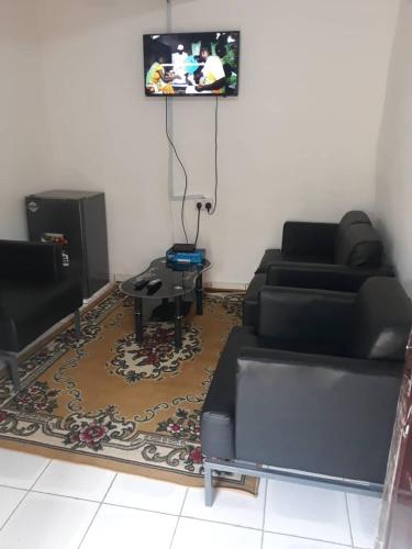 a living room with a couch and a tv at Mountains View Villa in Freetown