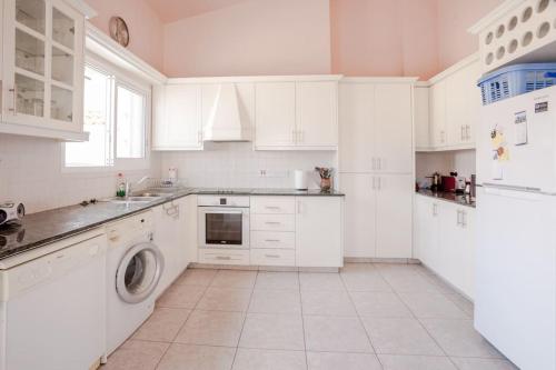 a white kitchen with white cabinets and a washer at Kisonerga Villa in Paphos in Kissonerga