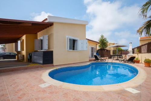 a swimming pool in front of a house at Kisonerga Villa in Paphos in Kissonerga