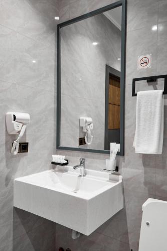 a bathroom with a white sink and a mirror at Diamond Hotel Shymkent in Shymkent