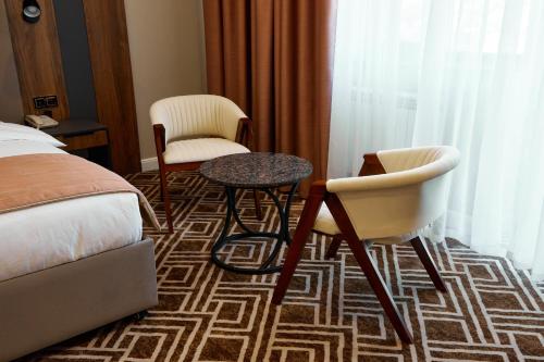 a hotel room with a bed and two chairs and a table at Diamond Hotel Shymkent in Shymkent