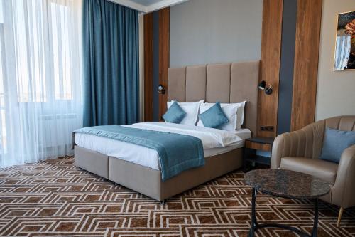 a hotel room with a bed and a chair at Diamond Hotel Shymkent in Shymkent