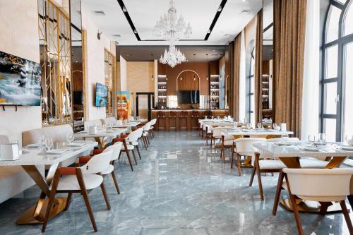 a restaurant with tables and chairs and a chandelier at Diamond Hotel Shymkent in Shymkent