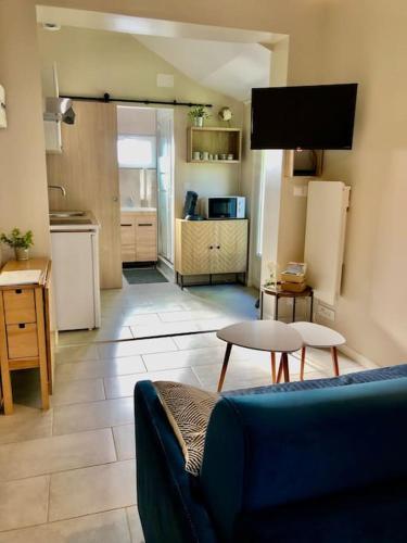 un salon avec un canapé et une cuisine dans l'établissement Les Embruns - Studio avec jardin, à Ouistreham