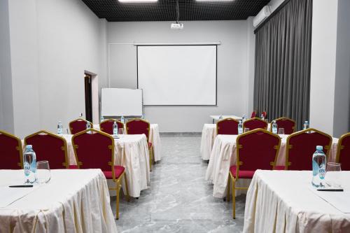 a conference room with tables and chairs and a whiteboard at Diamond Hotel Shymkent in Shymkent