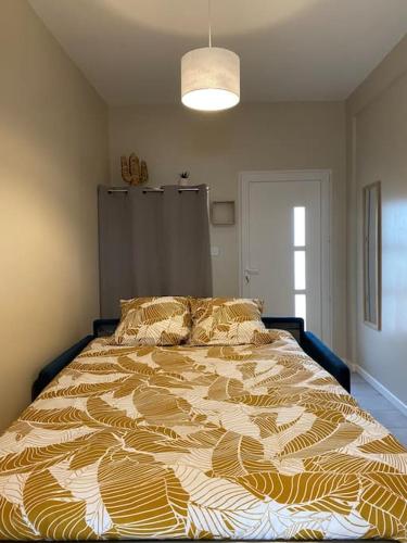 - une chambre avec un lit et une couette jaune et blanche dans l'établissement Les Embruns - Studio avec jardin, à Ouistreham