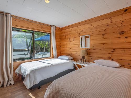 MatarangiにあるBeach Bliss Haven - Matarangi Holiday Homeの木製の壁と窓のある部屋にベッドが2つある