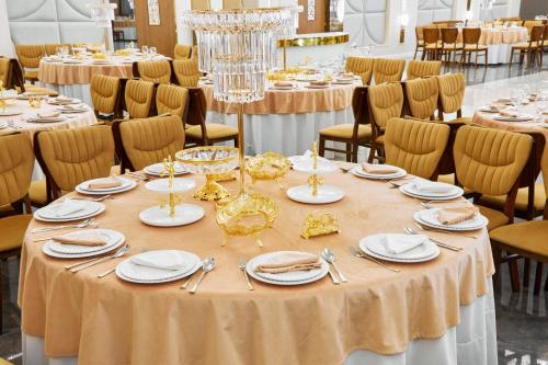 a table set up for a banquet with plates and silverware at Diamond Hotel Shymkent in Shymkent