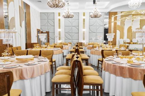 a banquet hall with tables and chairs and chandeliers at Diamond Hotel Shymkent in Shymkent