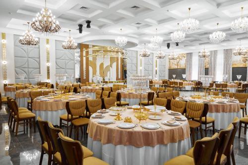 a ballroom with tables and chairs and chandeliers at Diamond Hotel Shymkent in Shymkent