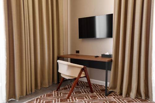 a desk with a television and a chair in a room at Diamond Hotel Shymkent in Shymkent