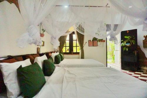 a bedroom with two beds with white drapes at Mekong Pottery Homestay, Green-Friendly & Boat Tour in Vĩnh Long