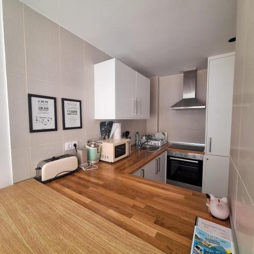 a kitchen with white cabinets and a wooden floor at Aliving Colo in Raxo